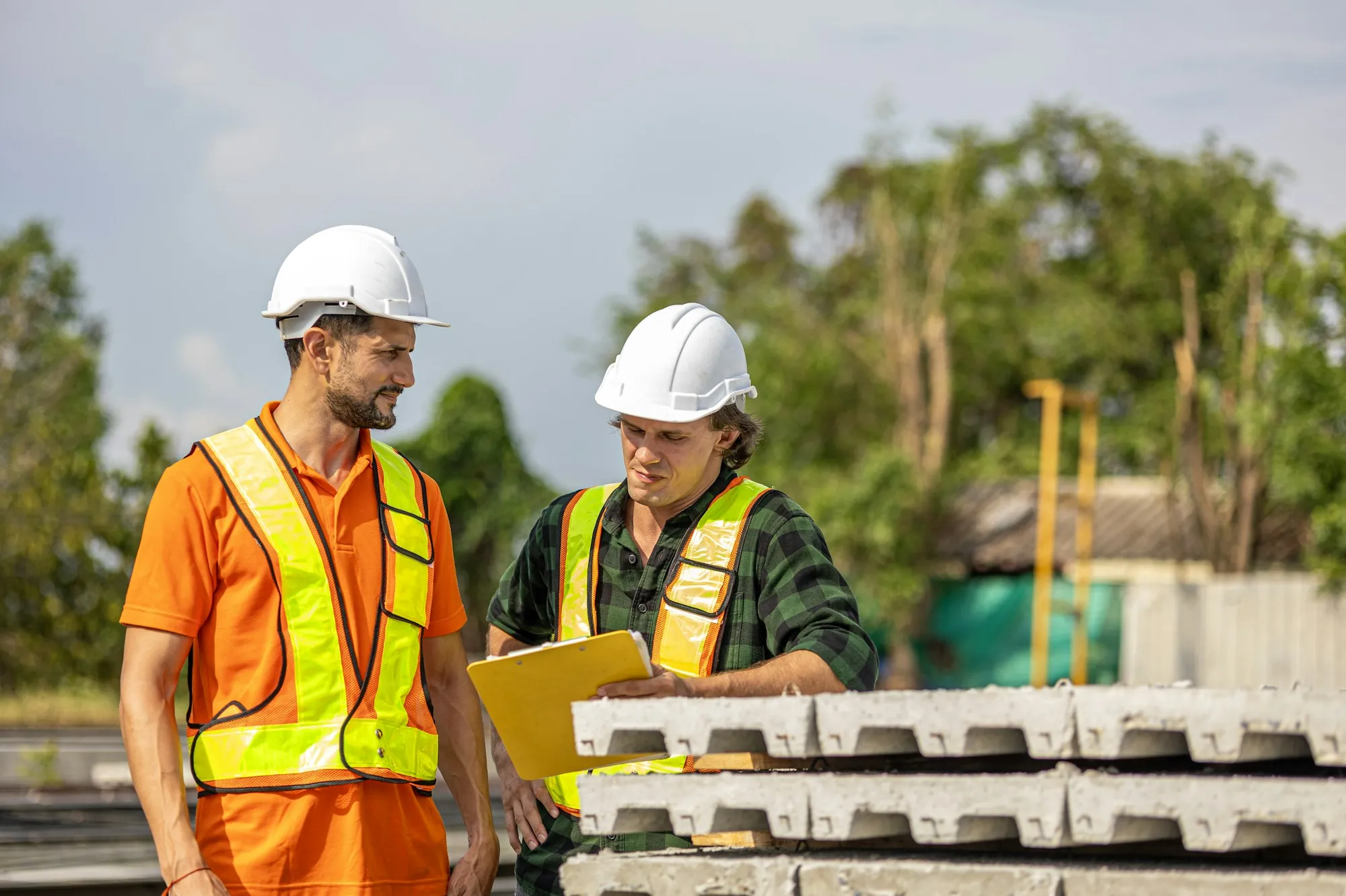 Two electricians reviewing a plan on a clipboard on site