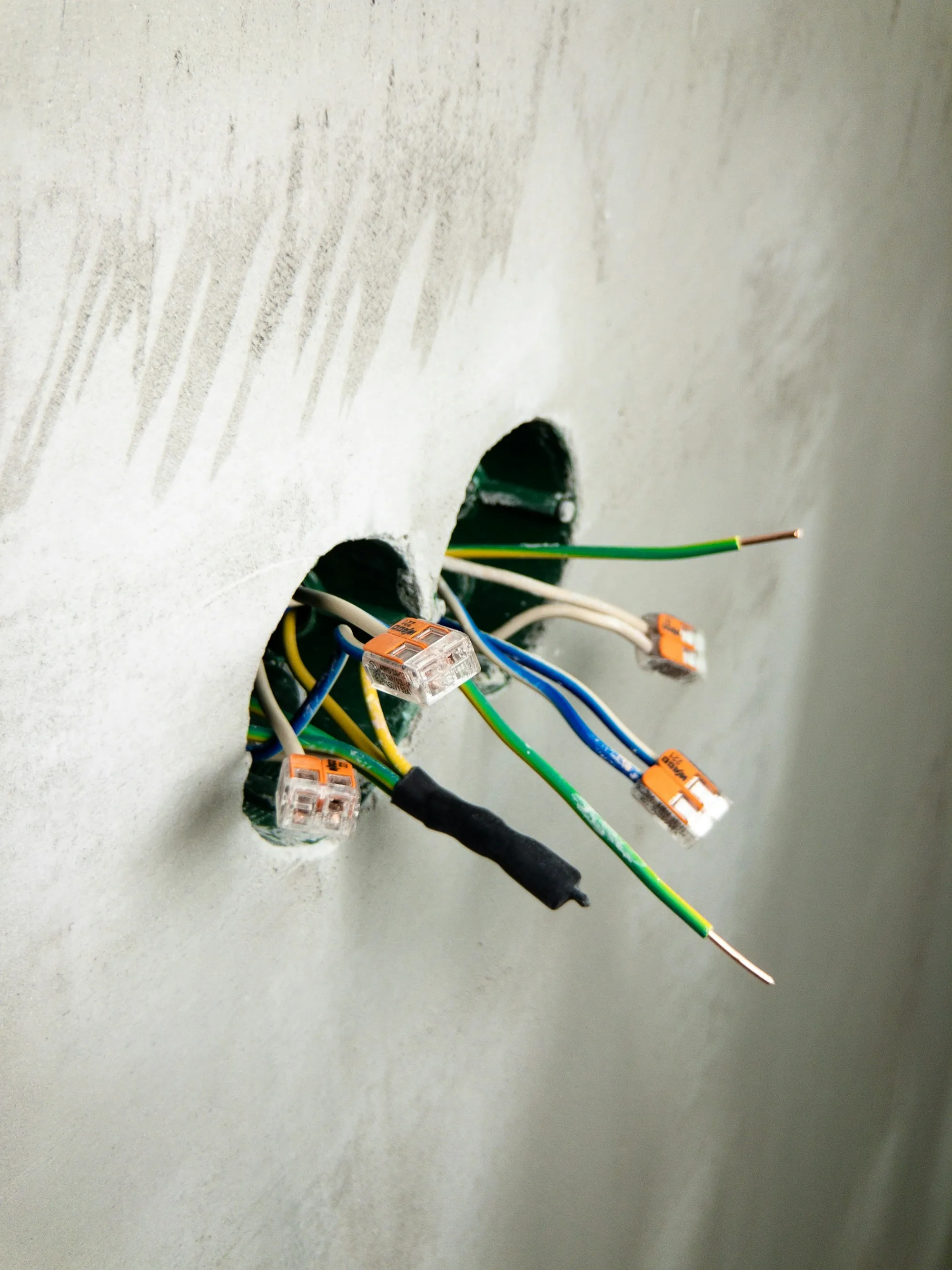 Bundled electrical wires coming through a white wall