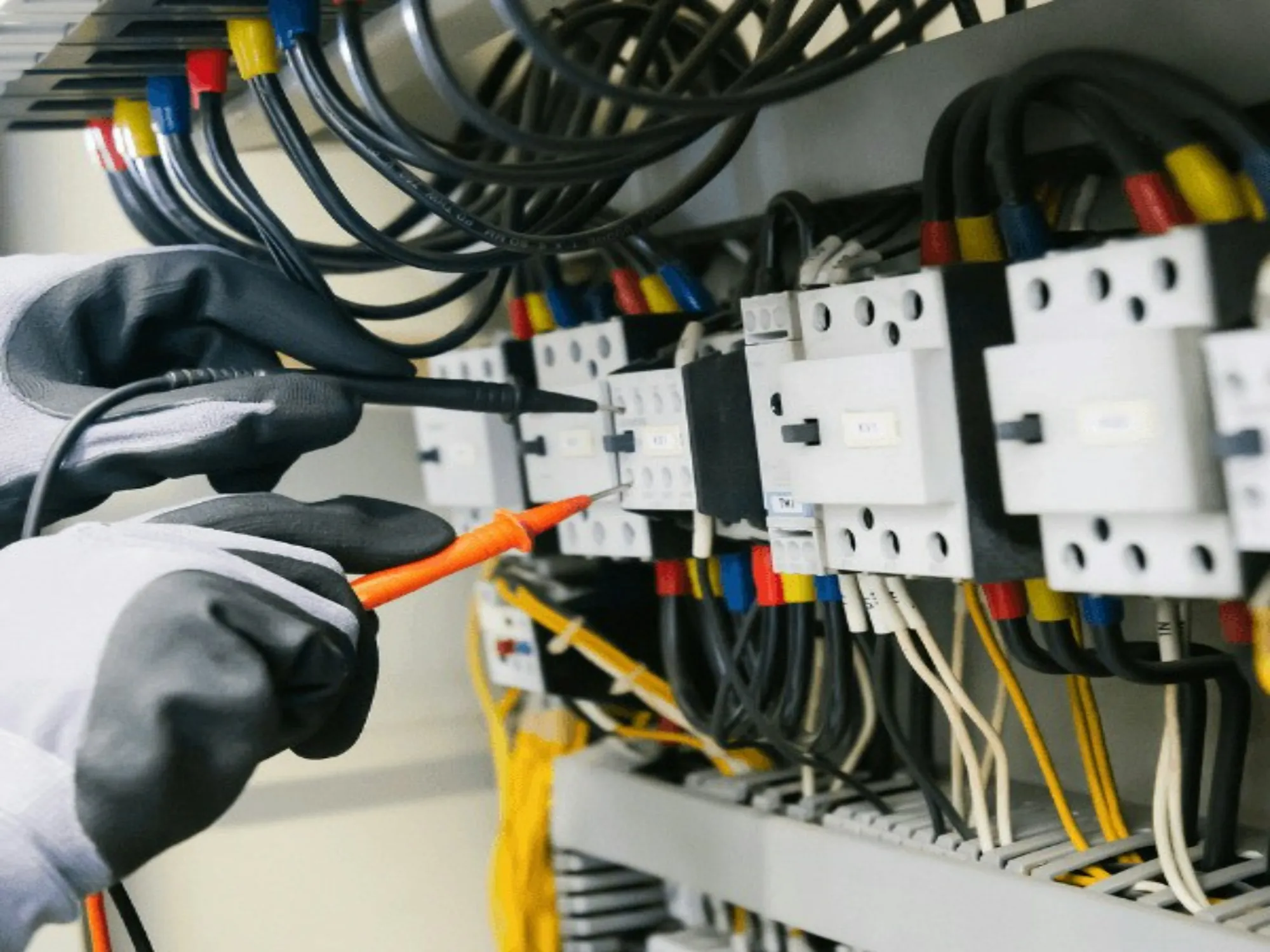 Tester probing breakers inside an electrical cabinet